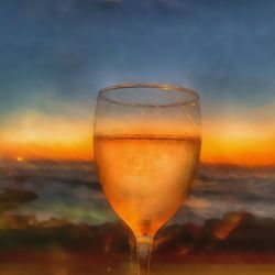 Close-up of beer glass against orange sky