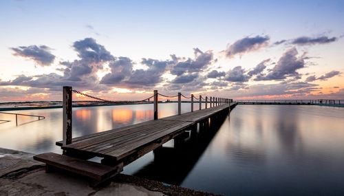 Pier over sea against sky during sunset