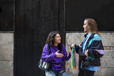 Two friends talking in the street outdoors with lgbt flag.