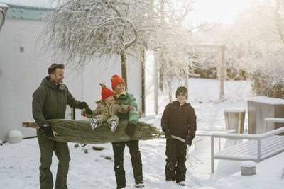 Family carrying christmas tree at winter