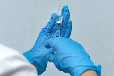 Close-up of man holding hands against blue wall