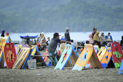 Rear view of people at beach against sky