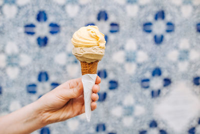 Female hand holding ice cream cone on blurred white blue background