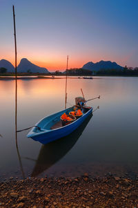 Boat moored on sea against sky at sunset