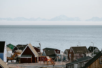 Houses by sea against sky