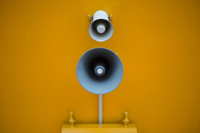 Close-up of loudspeaker on yellow wall