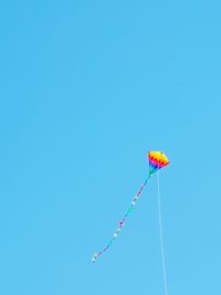 Low angle view of kite against clear blue sky