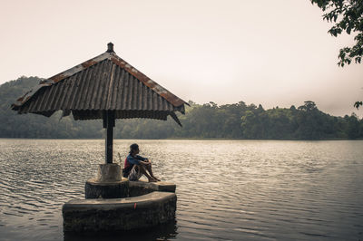 Young woman by lake against clear sky