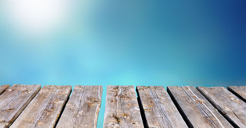 Close-up of wooden post by swimming pool against blue sky