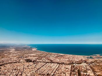 Aerial view of cityscape and sea against blue sky
