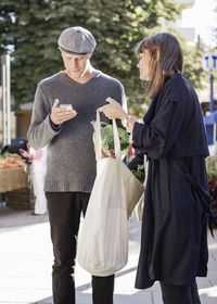 Couple checking list while shopping groceries at market