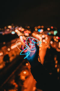 Cropped hand holding illuminated lights at night