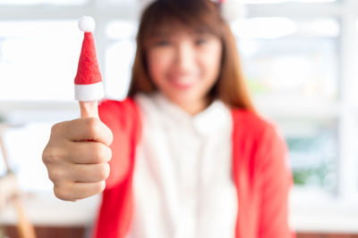 Close-up of woman wearing santa hats in fingers