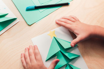 Cropped image of hand holding paper painting on table