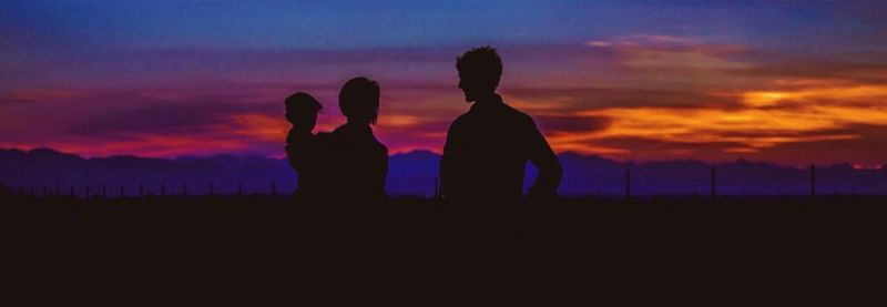 Silhouette people on field at sunset