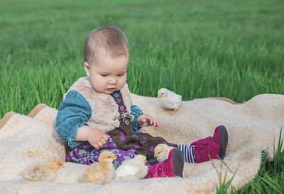 Portrait of cute baby boy lying on field