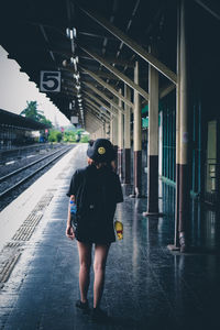 Rear view of woman standing at railroad station