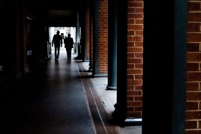 Rear view of silhouette men walking in colonnade