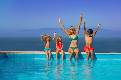 Rear view of woman with arms raised in swimming pool