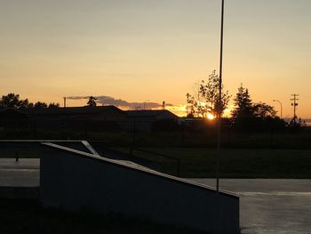 Road by silhouette trees against sky during sunset