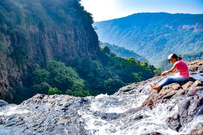 Woman sitting on rock looking at mountain