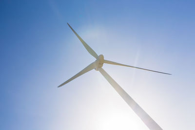 Low angle view of wind turbine against blue sky