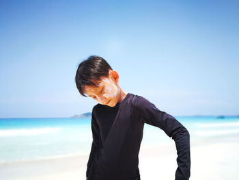 Boy standing on beach against sky