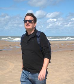 Portrait of young man standing at beach against sky