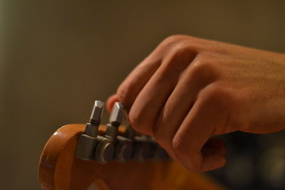 Cropped hand of guitarist tuning guitar