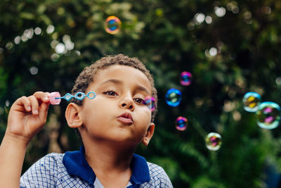 Boy blowing bubbles in park