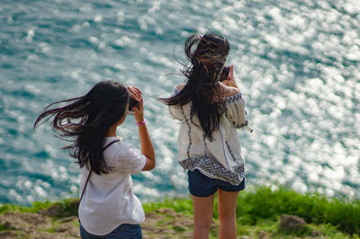 Women using mobile phone at lakeshore