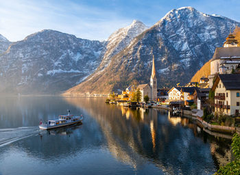 View of beautiful hallstatt lake and famous church during morning sunrise, tour boat coming in