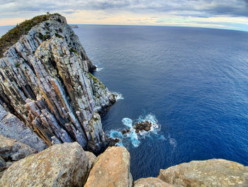 Rock formation on sea shore against sky