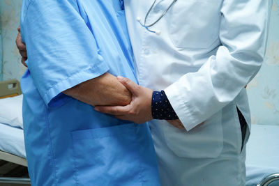 Midsection of doctor embracing patient while standing in hospital