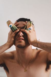 Man holding artificial eyes against wall at home