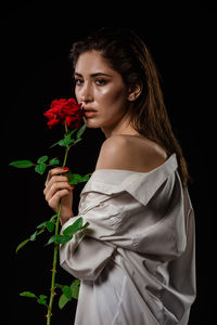 Young woman holding flower bouquet against black background