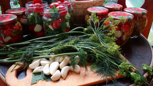 Close-up of garlic and dill on cutting board by jars at kitchen counter