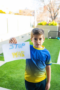 Little kid showing stop war banner with a ukranian t shirt