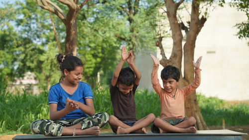 Happy kids is doing exercises in the summer park.