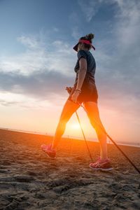 Woman standing on beach against sky during sunset