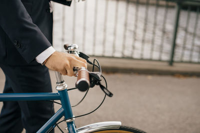 Midsection of businessman with bicycle on bridge in city