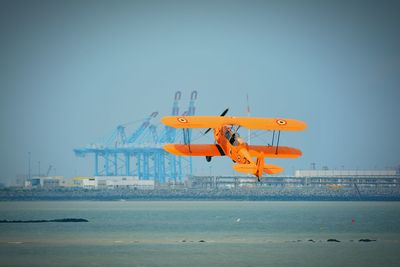 Aircraft flying over sea against clear sky