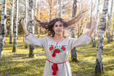 Beautiful woman in national ukrainian national traditional costume clothes walking in forest