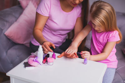 Daughter applying nail polish to mother at home