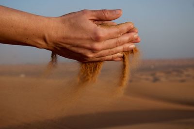 Close-up side view of hands holding sand