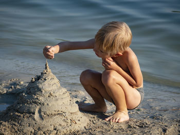 Cute boy making sandcastle at lakeshore