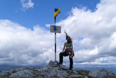 Low angle view of man standing on rock against sky