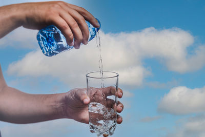 Midsection of person holding ice cream cone against sky