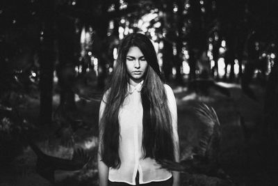 Portrait of young woman standing against trees