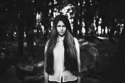 Portrait of young woman standing against trees